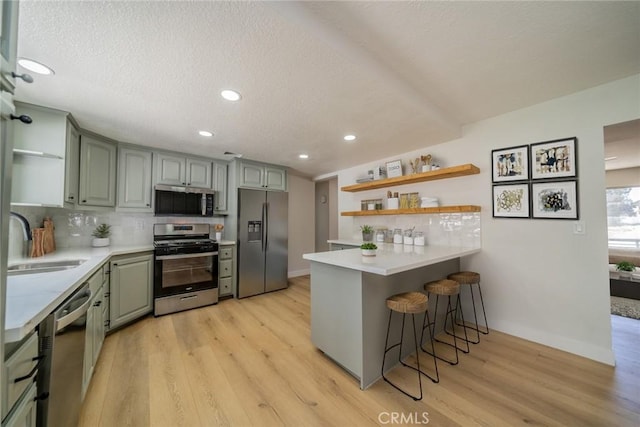 28732 Paseo Diablo, Menifee, CA 92587 - kitchen featuring open shelves, appliances with stainless steel finishes, a sink, a peninsula, and light wood-style flooring