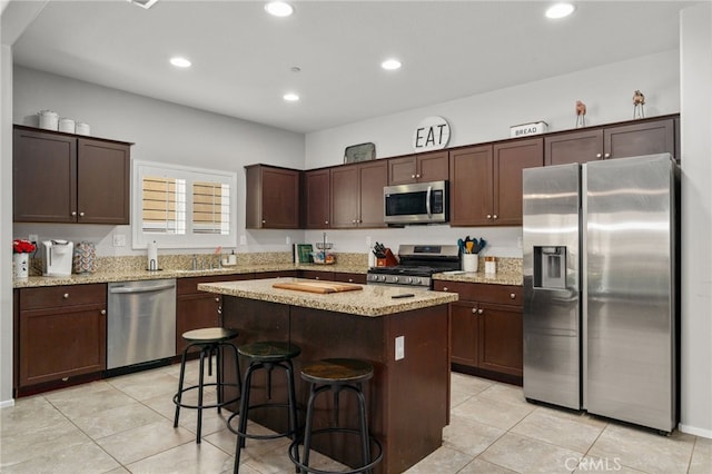 33007 Cattle Dr, Winchester, CA 92596 - kitchen with stainless steel appliances, light tile patterned floors, dark brown cabinets, a kitchen island, and light stone countertops