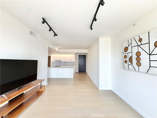 1050 S Grand Ave Unit 2003, Los Angeles, CA 90015 - unfurnished living room with rail lighting, light wood-style flooring, baseboards, and a sink