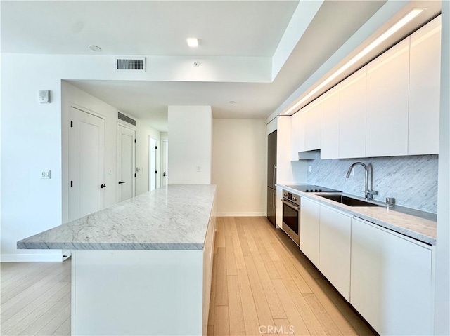 1050 S Grand Ave Unit 2003, Los Angeles, CA 90015 - kitchen with stainless steel oven, a sink, baseboards, a kitchen island, and light wood-style flooring