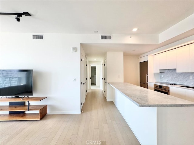 1050 S Grand Ave Unit 2003, Los Angeles, CA 90015 - kitchen with oven, light countertops, modern cabinets, white cabinets, and light wood-style floors