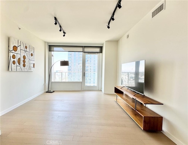 1050 S Grand Ave Unit 2003, Los Angeles, CA 90015 - unfurnished living room featuring rail lighting, wood finished floors, and baseboards