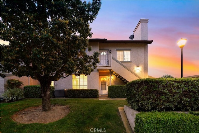 155 Oxford Unit 37, Irvine, CA 92612 - view of front facade featuring a lawn, stucco siding, a chimney, and central air condition unit