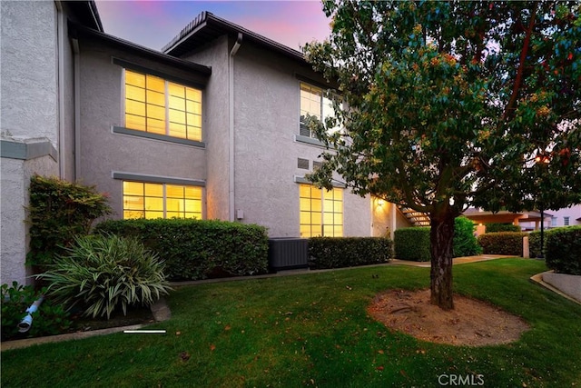 155 Oxford Unit 37, Irvine, CA 92612 - property exterior at dusk featuring stucco siding, a yard, and central air condition unit