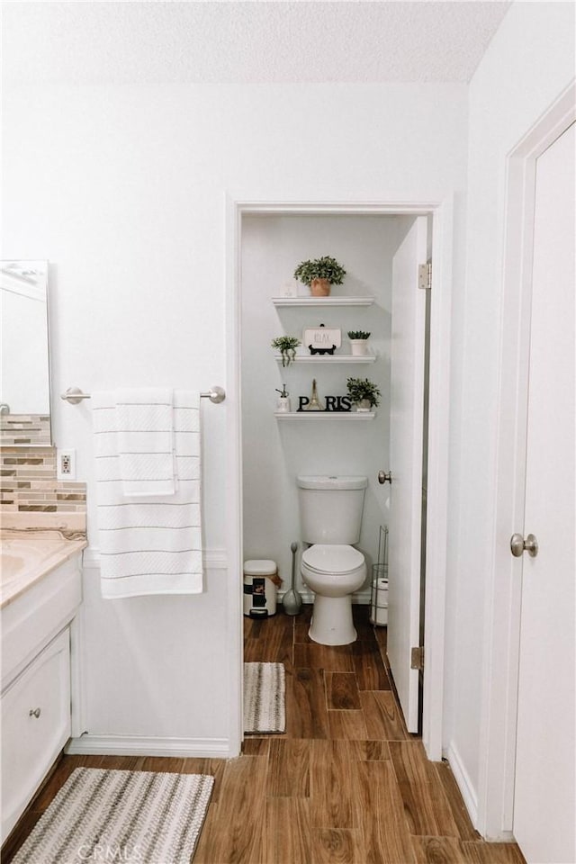 134 N American St, Ridgecrest, CA 93555 - bathroom with wood finished floors, vanity, toilet, and backsplash