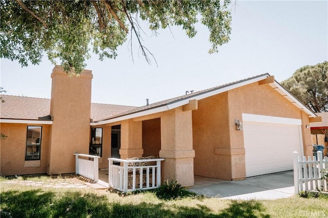 134 N American St, Ridgecrest, CA 93555 - view of front of house with a chimney, a garage, and stucco siding