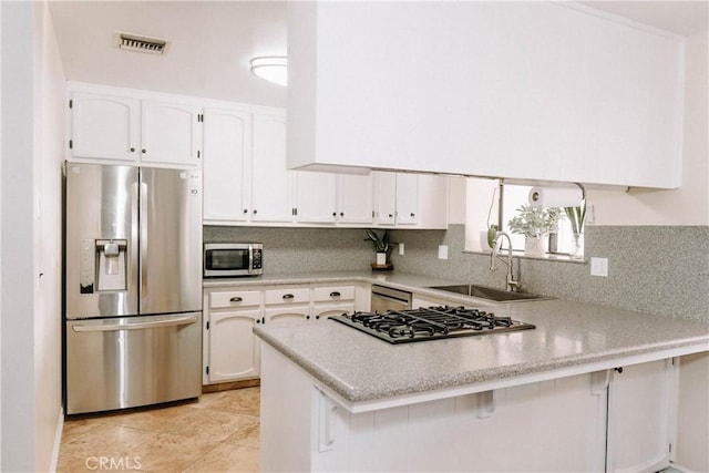 134 N American St, Ridgecrest, CA 93555 - kitchen with stainless steel appliances, a sink, a peninsula, white cabinetry, and light countertops