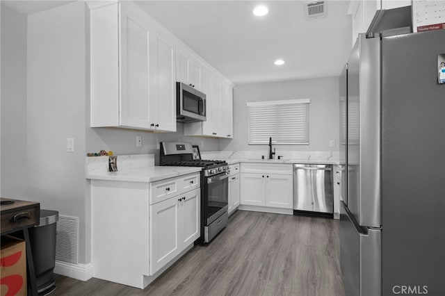 4622 San Jose St Unit W, Montclair, CA 91763 - kitchen with stainless steel appliances, a sink, wood finished floors, recessed lighting, and white cabinets
