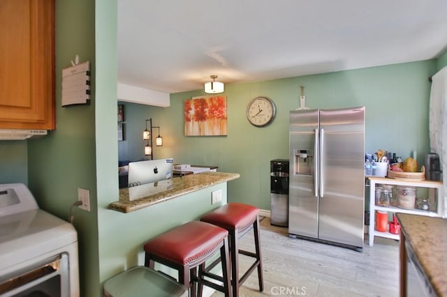 4502 Bates Dr, Yorba Linda, CA 92886 - kitchen featuring stainless steel refrigerator with ice dispenser, washer / clothes dryer, light wood finished floors, a kitchen breakfast bar, and light stone counters