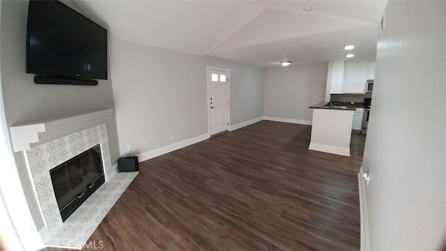 2400 Del Mar Way Unit 206, Corona, CA 92882 - unfurnished living room with baseboards, dark wood-style floors, lofted ceiling, a premium fireplace, and a sink
