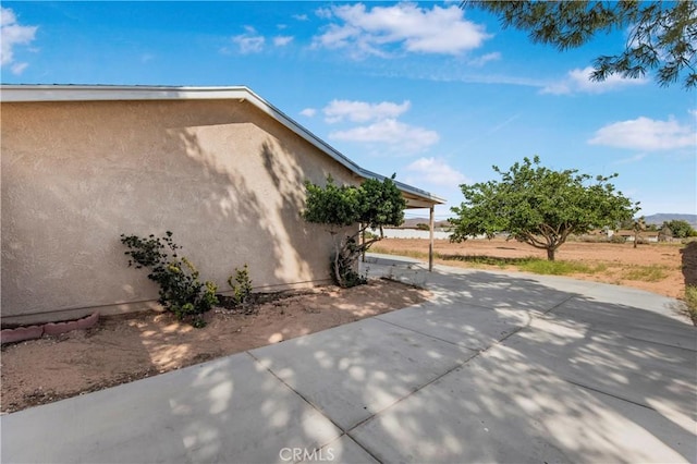 14317 Jicarilla Rd, Apple Valley, CA 92307 - view of side of property featuring stucco siding, a patio area, and concrete driveway