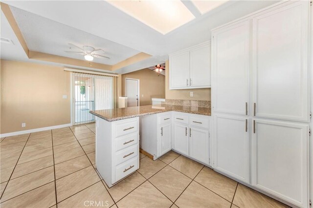 14317 Jicarilla Rd, Apple Valley, CA 92307 - kitchen featuring a ceiling fan, white cabinetry, a peninsula, and light tile patterned flooring