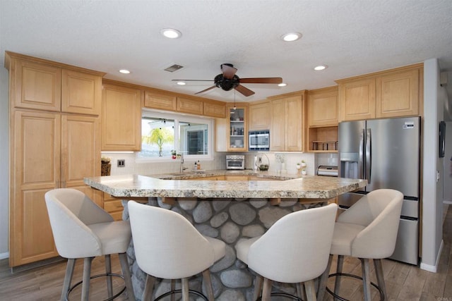 29730 Red Mountain Rd, Valley Center, CA 92082 - kitchen featuring appliances with stainless steel finishes, wood finished floors, a kitchen breakfast bar, a center island, and decorative backsplash