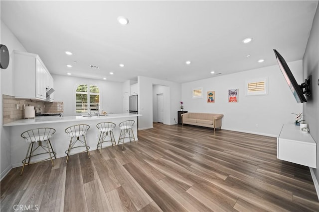 16007 Dexter St, Chino, CA 91708 - kitchen featuring a breakfast bar, recessed lighting, a peninsula, wood finished floors, and white cabinets