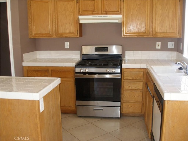 12975 Stanford Dr, Victorville, CA 92392 - kitchen featuring under cabinet range hood, stainless steel range with gas cooktop, a sink, light tile patterned flooring, and tile countertops