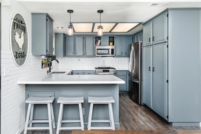 23912 Benito Way, Ramona, CA 92065 - kitchen with appliances with stainless steel finishes, a peninsula, tasteful backsplash, hanging light fixtures, and dark wood-style floors