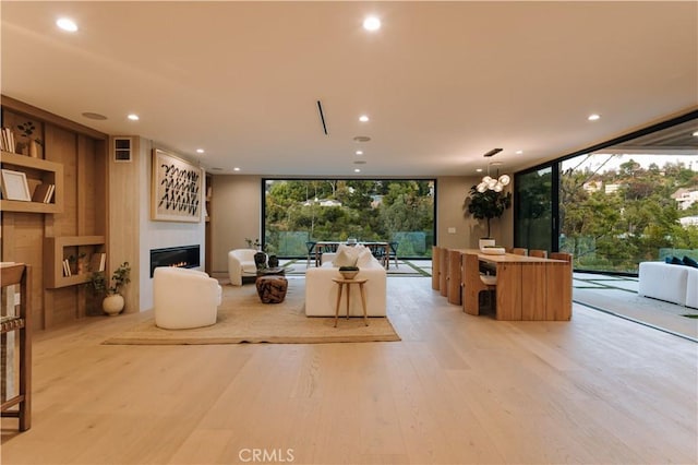 2608 Zorada Dr, Los Angeles, CA 90046 - living area featuring a warm lit fireplace, floor to ceiling windows, light wood-style flooring, and recessed lighting