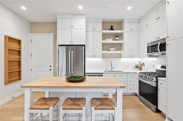 108 Coastal Gdn, Irvine, CA 92618 - kitchen with stainless steel appliances, a sink, open shelves, a breakfast bar area, and white cabinets