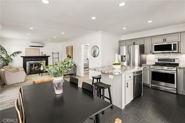 5893 E Adderley Dr, Long Beach, CA 90808 - kitchen with appliances with stainless steel finishes, a wall mounted AC, gray cabinetry, a center island, and light stone counters