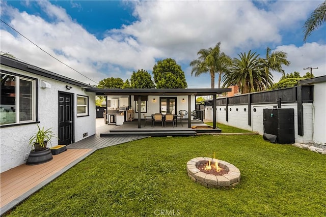 5893 E Adderley Dr, Long Beach, CA 90808 - back of house featuring a wooden deck, a fire pit, a lawn, and stucco siding