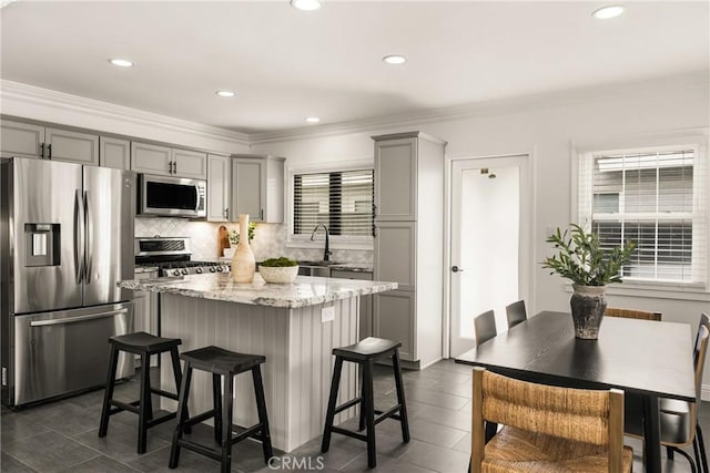 5893 E Adderley Dr, Long Beach, CA 90808 - kitchen with appliances with stainless steel finishes, gray cabinets, a kitchen island, a breakfast bar area, and crown molding