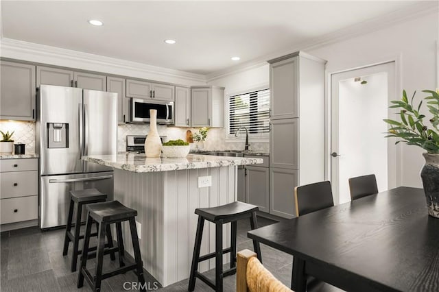 5893 E Adderley Dr, Long Beach, CA 90808 - kitchen featuring stainless steel appliances, gray cabinetry, a kitchen island, tasteful backsplash, and a kitchen bar