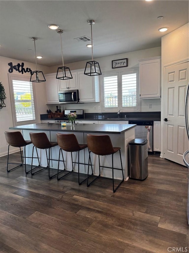 31827 Ives Ct, Menifee, CA 92584 - kitchen featuring appliances with stainless steel finishes, white cabinets, dark countertops, a kitchen breakfast bar, and recessed lighting