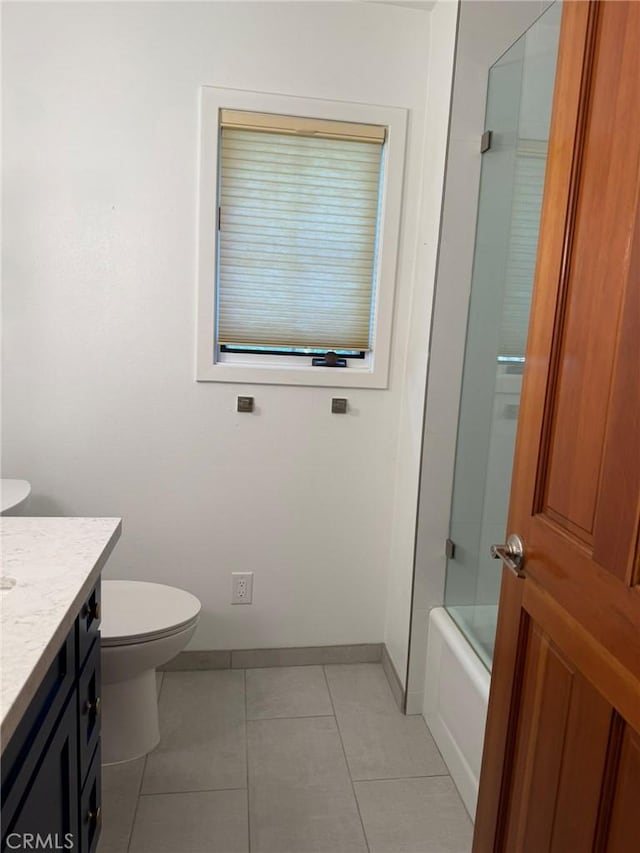 117 S Park Dr, Madera, CA 93637 - bathroom with vanity, toilet, tile patterned flooring, baseboards, and combined bath / shower with glass door