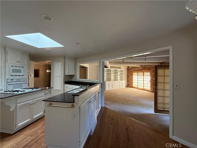 117 S Park Dr, Madera, CA 93637 - kitchen featuring white appliances, dark countertops, white cabinetry, and a skylight