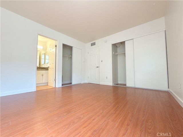 8601 International Ave Unit 179, Canoga Park, CA 91304 - unfurnished bedroom with two closets, wood finished floors, baseboards, and connected bathroom
