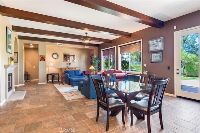 36235 Bay Hill Dr, Beaumont, CA 92223 - dining room with stone tile floors, beamed ceiling, baseboards, a ceiling fan, and a fireplace with flush hearth