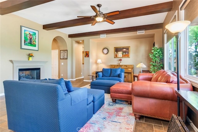 36235 Bay Hill Dr, Beaumont, CA 92223 - living area featuring beam ceiling, arched walkways, a ceiling fan, healthy amount of natural light, and a glass covered fireplace