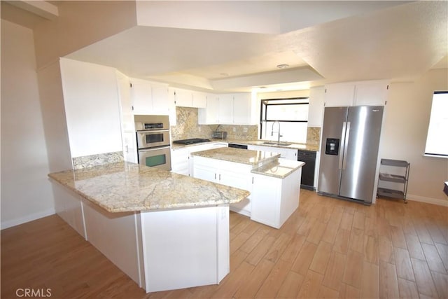 14279 Galleon Ln, Helendale, CA 92342 - kitchen with appliances with stainless steel finishes, a raised ceiling, a sink, baseboards, and light wood-style floors