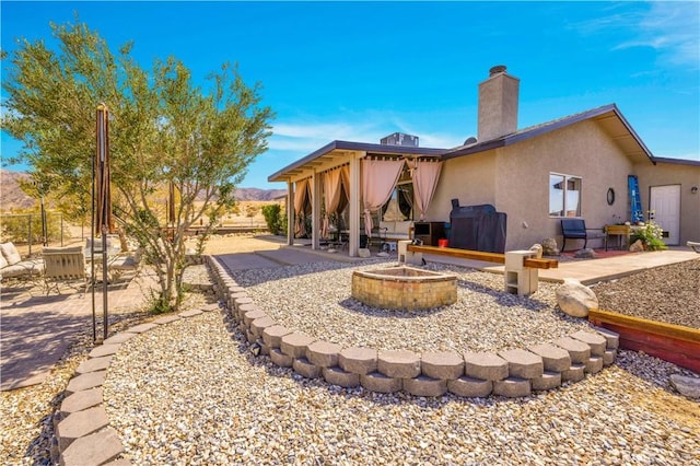 6279 Baileya Ave Unit 29, Palms, CA 92277 - back of property with a fire pit, a patio, a chimney, and stucco siding