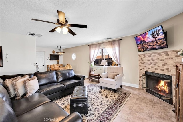 6279 Baileya Ave Unit 29, Palms, CA 92277 - living room featuring a ceiling fan, a textured ceiling, light tile patterned floors, a brick fireplace, and baseboards