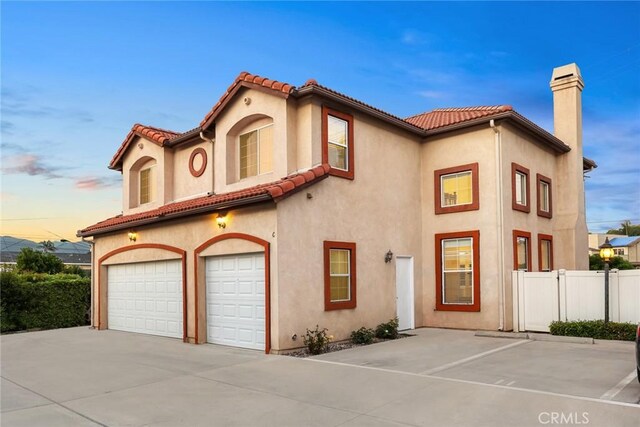4937 Peck Rd Unit C, El Monte, CA 91732 - mediterranean / spanish house featuring a garage, a chimney, stucco siding, concrete driveway, and a tiled roof