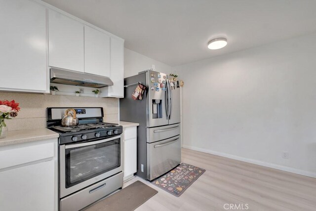 7701 Baird Ave, Reseda, CA 91335 - kitchen with appliances with stainless steel finishes, under cabinet range hood, light wood finished floors, light countertops, and decorative backsplash