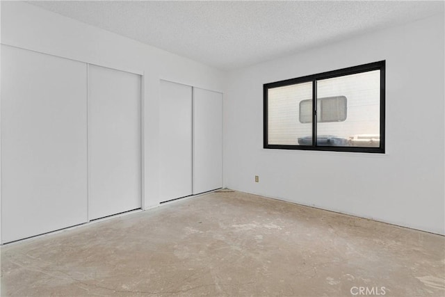 9820 Mandalay Ct, Riverside, CA 92503 - unfurnished bedroom featuring two closets, concrete floors, and a textured ceiling