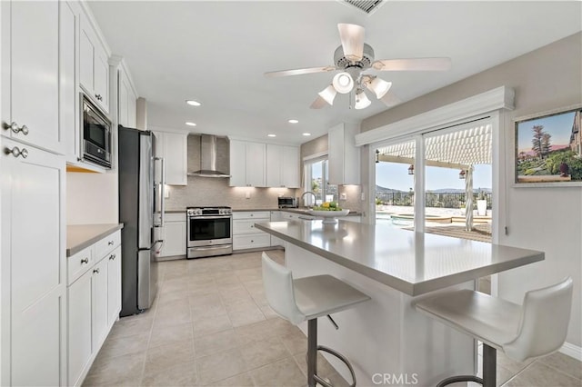 32070 Corte Bonilio, Temecula, CA 92592 - kitchen with appliances with stainless steel finishes, wall chimney exhaust hood, a breakfast bar, backsplash, and light tile patterned floors