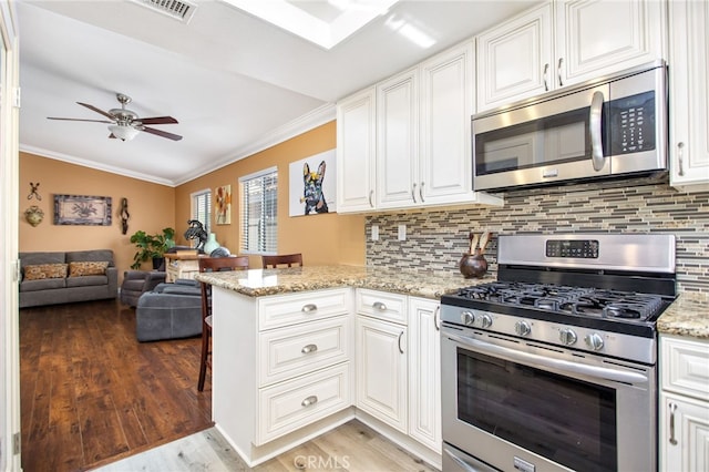 28162 Bavaria Dr, Menifee, CA 92585 - kitchen with appliances with stainless steel finishes, crown molding, light wood finished floors, open floor plan, and a ceiling fan