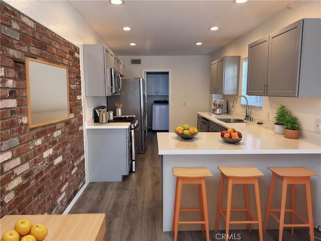 23308 Friar St, Woodland Hills, CA 91367 - kitchen featuring appliances with stainless steel finishes, gray cabinetry, dark wood finished floors, recessed lighting, and brick wall