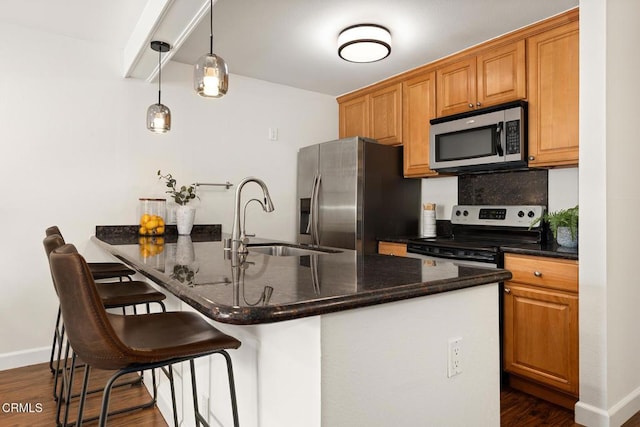 4000 Via Marisol 103, Los Angeles, CA 90042 - kitchen with stainless steel appliances, a sink, a kitchen bar, dark wood-type flooring, and baseboards