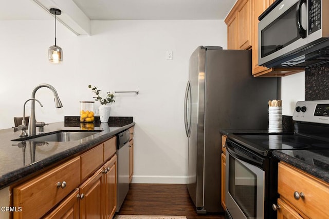4000 Via Marisol 103, Los Angeles, CA 90042 - kitchen with stainless steel appliances, a sink, baseboards, dark wood finished floors, and brown cabinetry