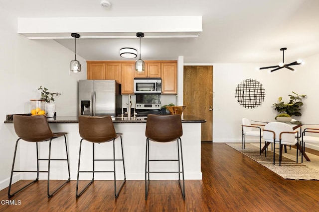 4000 Via Marisol 103, Los Angeles, CA 90042 - kitchen featuring stainless steel appliances, a kitchen breakfast bar, dark wood finished floors, pendant lighting, and a peninsula