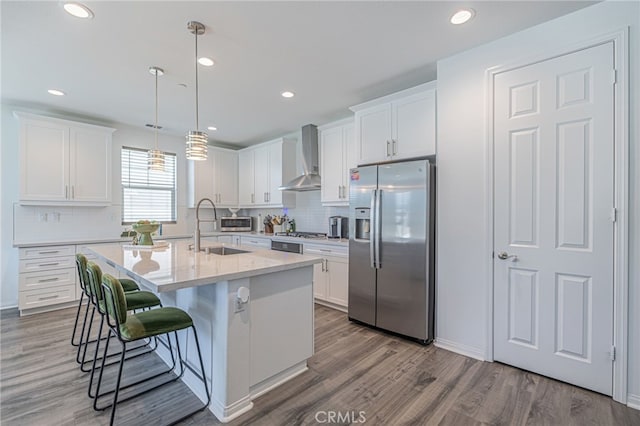 6118 W W Ave J9, Lancaster, CA 93536 - kitchen with stainless steel fridge with ice dispenser, a sink, wall chimney range hood, a breakfast bar, and white cabinets