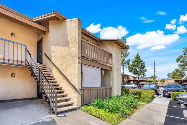 10296 Black Mountain Rd Unit 222, San Diego, CA 92126 - view of property exterior featuring stucco siding, stairway, and uncovered parking