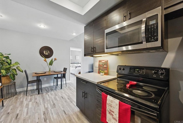 10296 Black Mountain Rd Unit 222, San Diego, CA 92126 - kitchen with black range with electric stovetop, stainless steel microwave, light wood finished floors, light countertops, and baseboards