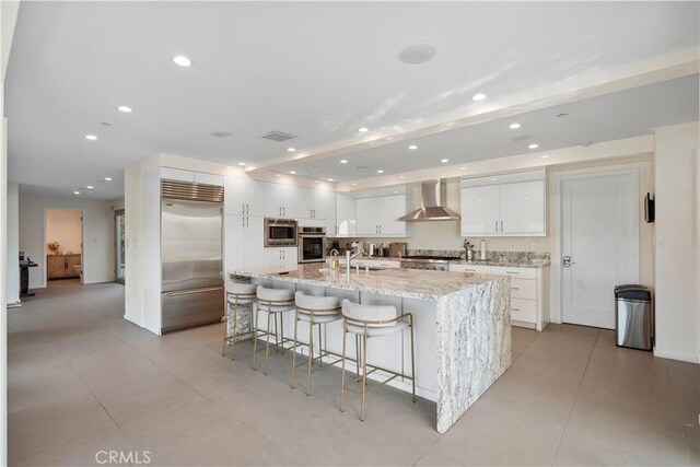 9716 Oak Pass Rd, Beverly Hills, CA 90210 - kitchen featuring built in appliances, wall chimney exhaust hood, recessed lighting, white cabinetry, and a spacious island