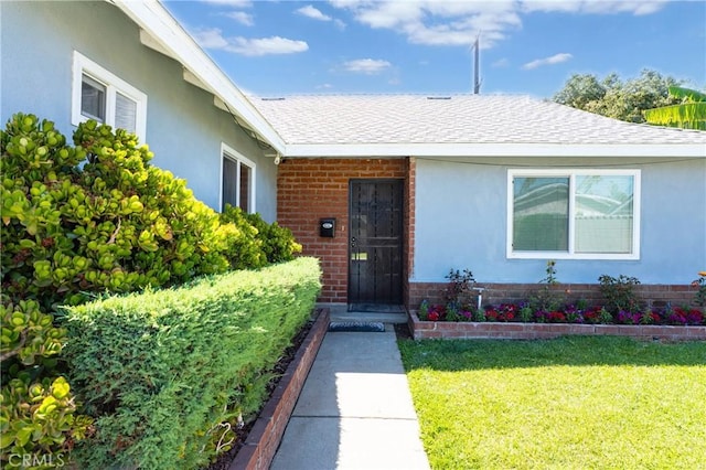 3624 Ardilla Ave, Baldwin Park, CA 91706 - property entrance featuring brick siding, a lawn, stucco siding, and a shingled roof