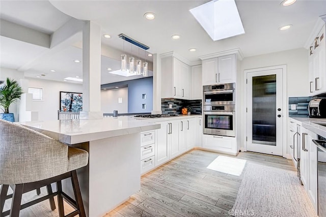 417 23rd St, Manhattan Beach, CA 90266 - kitchen with appliances with stainless steel finishes, light wood-type flooring, decorative backsplash, white cabinetry, and hanging light fixtures